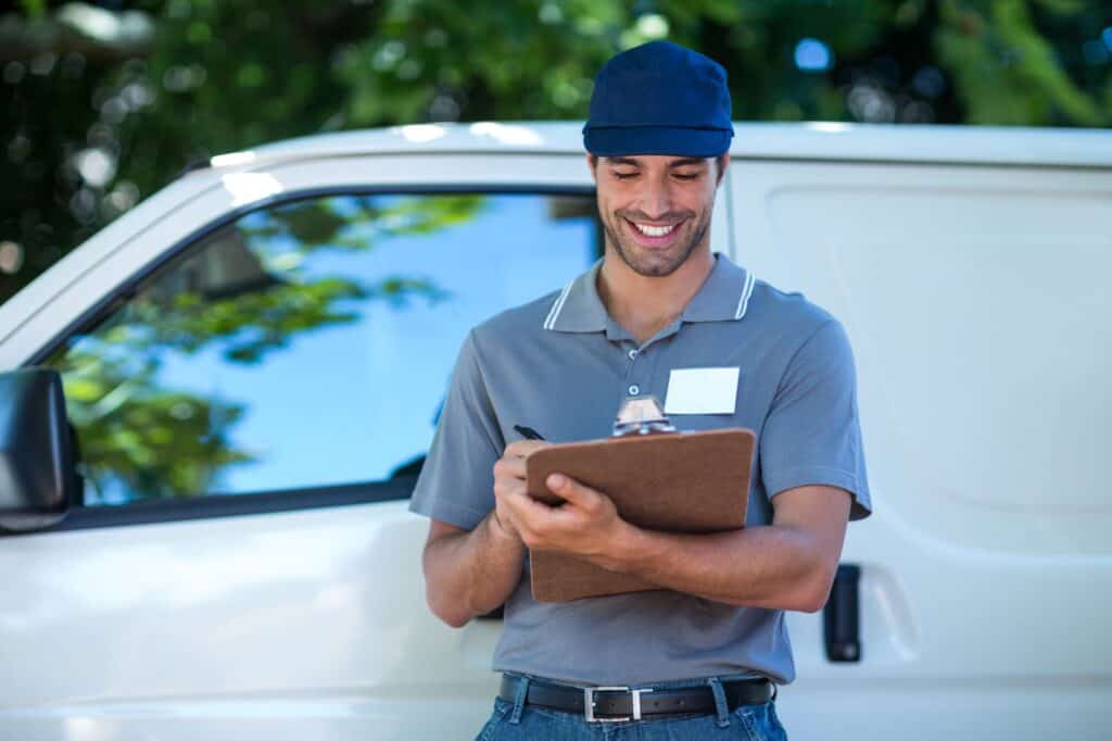 A happy Man And Van employee is holding a checklist