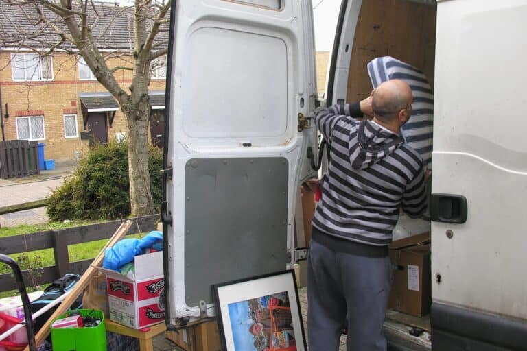 A mover placing a bed mattress inside the van